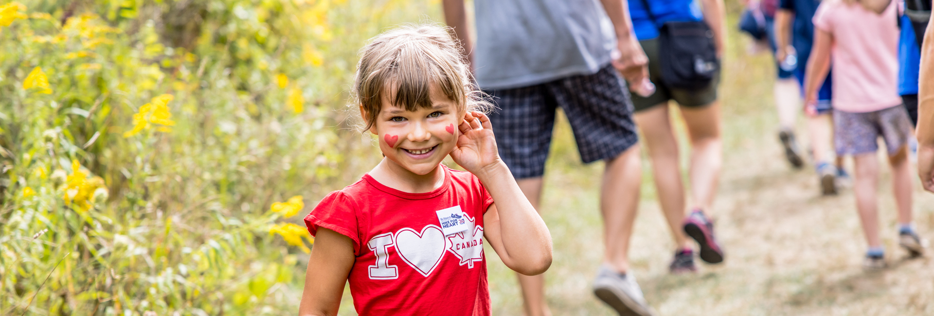 Happy girl enjoying hike for heart with her face painted.